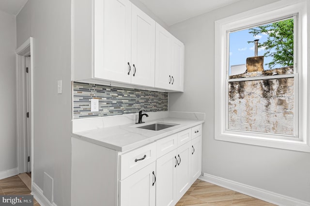 755 S 22nd St, Philadelphia, PA 19146 - kitchen with a sink, backsplash, baseboards, light stone countertops, and white cabinets