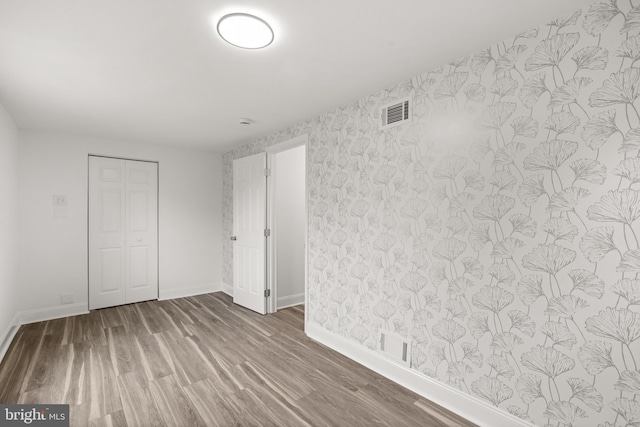 1164 Fairfax Pike, White Post, VA 22663 - unfurnished bedroom featuring baseboards, wood finished floors, wallpapered walls, and a closet