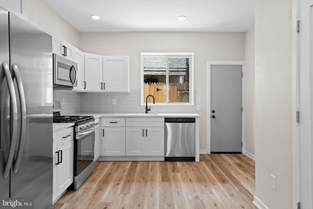 1728 S Bancroft St, Philadelphia, PA 19145 - kitchen featuring appliances with stainless steel finishes, a sink, light countertops, backsplash, and white cabinets
