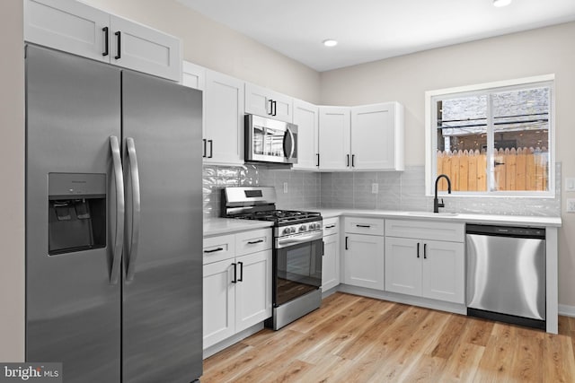 1728 S Bancroft St, Philadelphia, PA 19145 - kitchen featuring appliances with stainless steel finishes, a sink, light countertops, decorative backsplash, and white cabinets
