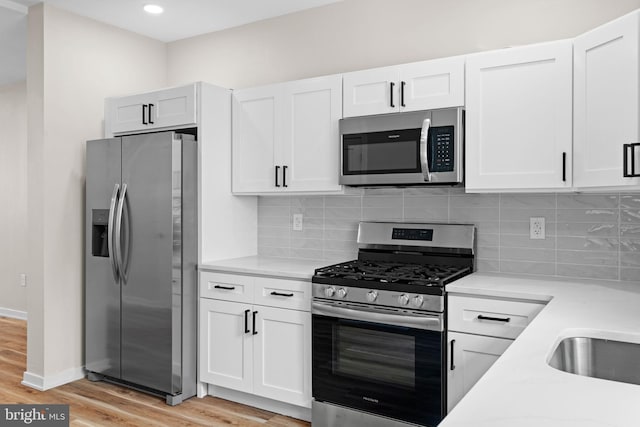 1728 S Bancroft St, Philadelphia, PA 19145 - kitchen with appliances with stainless steel finishes, light wood finished floors, white cabinetry, backsplash, and recessed lighting