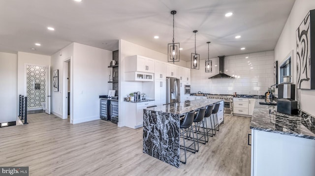 21 Hart Ln, Ventnor City, NJ 08406 - kitchen with wall chimney range hood, stainless steel appliances, a center island, dark stone counters, and light wood-style flooring