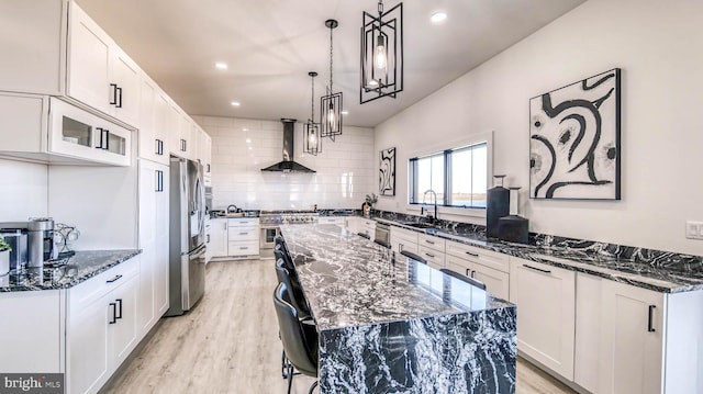 21 Hart Ln, Ventnor City, NJ 08406 - kitchen with stainless steel appliances, wall chimney exhaust hood, a center island, light wood-style flooring, and dark stone countertops