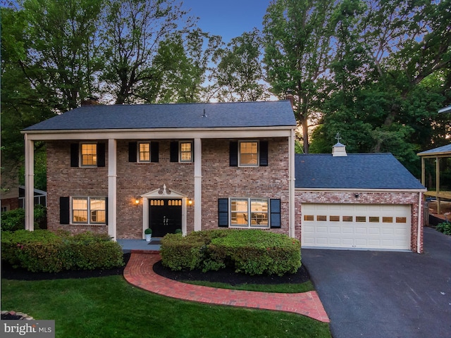 1334 Elsinore Ave, Mclean, VA 22102 - greek revival house with asphalt driveway, a garage, a chimney, and brick siding