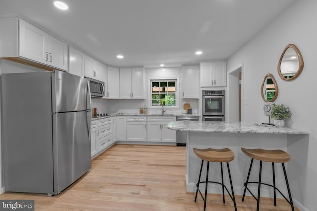 1334 Elsinore Ave, Mclean, VA 22102 - kitchen featuring appliances with stainless steel finishes, a sink, a peninsula, light stone counters, and white cabinetry