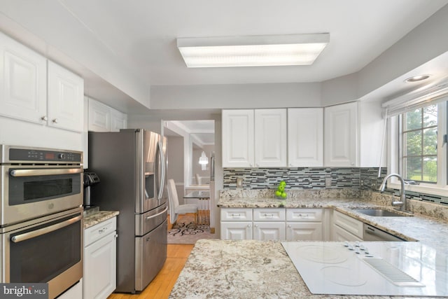 9710 Magledt Rd, Baltimore, MD 21234 - kitchen featuring appliances with stainless steel finishes, light wood-type flooring, light stone countertops, and white cabinetry