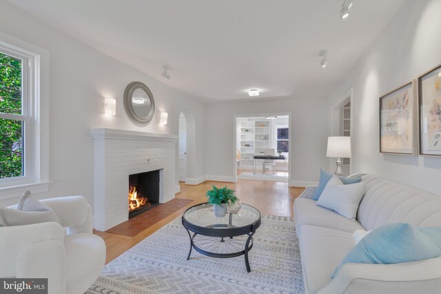 5001 14th St N, Arlington, VA 22205 - living room with light wood-style flooring, rail lighting, a brick fireplace, and baseboards
