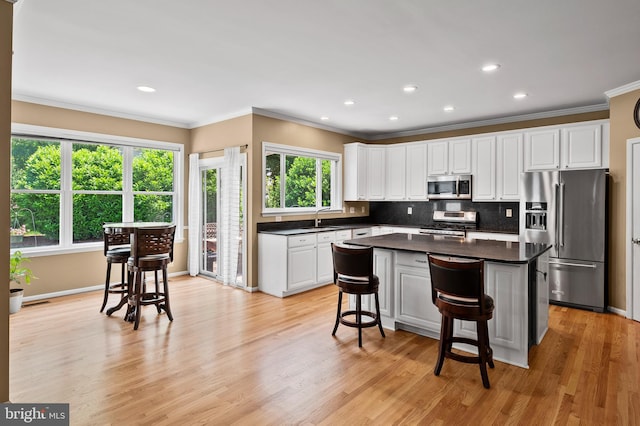 10604 Sourwood Ct, Laurel, MD 20723 - kitchen with stainless steel appliances, white cabinetry, dark countertops, decorative backsplash, and crown molding