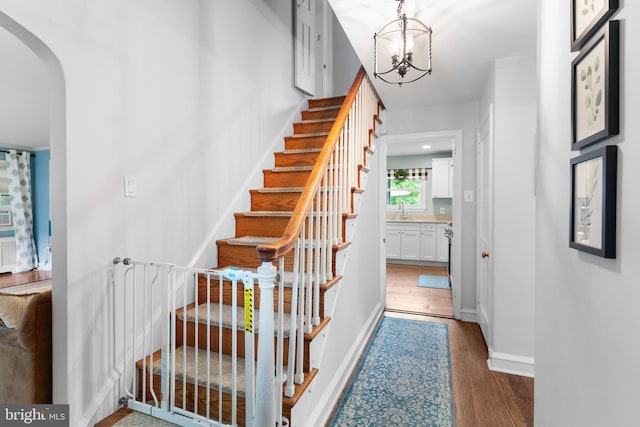 625 Lindley Rd, Glenside, PA 19038 - stairs featuring arched walkways, wood finished floors, a chandelier, and baseboards