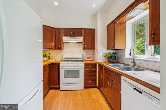 9101 Sligo Creek Pkwy, Silver Spring, MD 20901 - kitchen featuring white appliances, under cabinet range hood, light wood finished floors, light countertops, and backsplash