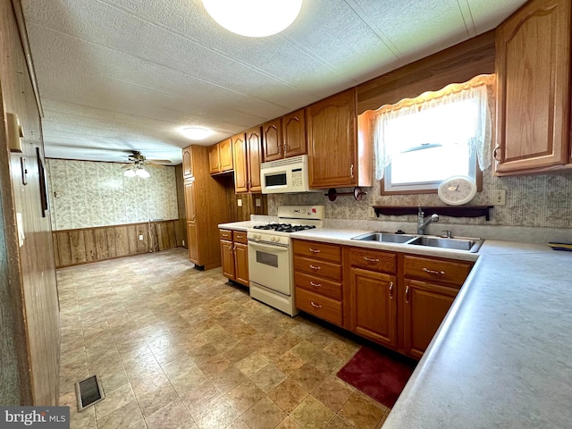 1609 Powell Ave, Hyde, PA 16843 - kitchen featuring white appliances, a sink, light countertops, brown cabinetry, and a wainscoted wall