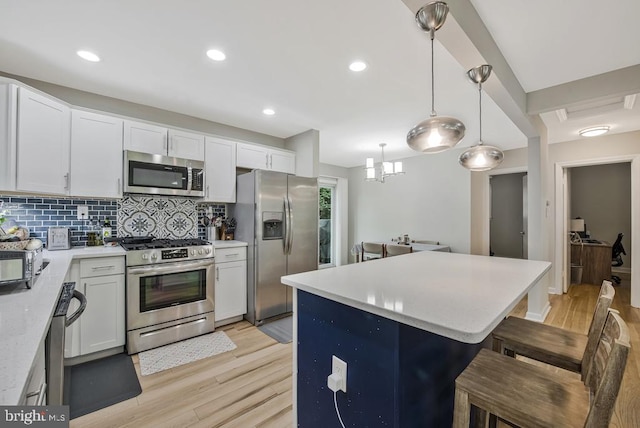 11008 Madison St, Kensington, MD 20895 - kitchen with appliances with stainless steel finishes, light wood-style flooring, a breakfast bar, a kitchen island, and recessed lighting