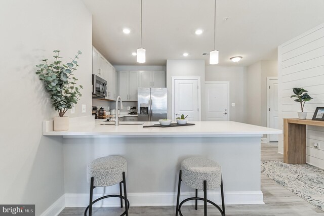 406-203 Bold Ruler Ct, Havre De Grace, MD 21078 - kitchen with appliances with stainless steel finishes, a sink, a peninsula, light wood-style flooring, and a breakfast bar area
