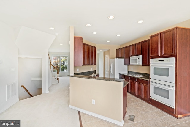 9207 Cascade Falls Dr, Bristow, VA 20136 - kitchen featuring white appliances, recessed lighting, a peninsula, dark stone countertops, and light tile patterned flooring
