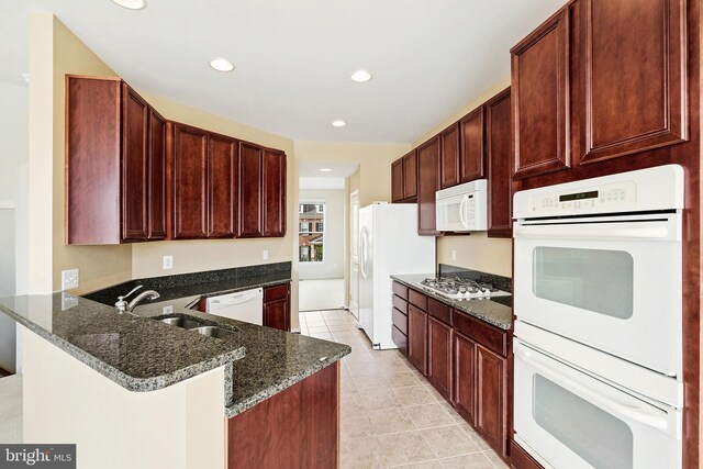 9207 Cascade Falls Dr, Bristow, VA 20136 - kitchen with white appliances, a sink, dark stone countertops, a peninsula, and recessed lighting