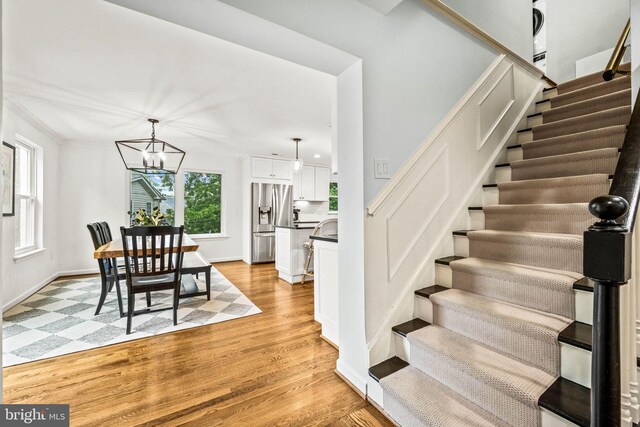 3311 Cameron Mills Rd, Alexandria, VA 22302 - dining space with stairs, a chandelier, light wood-style floors, and baseboards