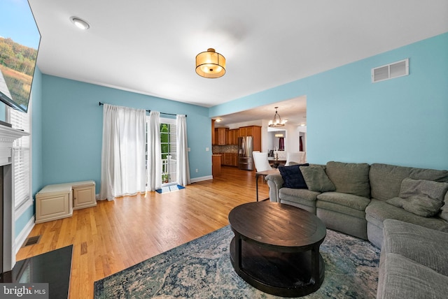 143 Oak St, Bridgewater, NJ 08807 - living room featuring light wood finished floors, a chandelier, a fireplace, and baseboards