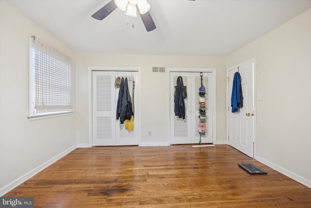2722 E Riding Dr, Wilmington, DE 19808 - unfurnished bedroom featuring multiple closets, wood finished floors, baseboards, and a ceiling fan