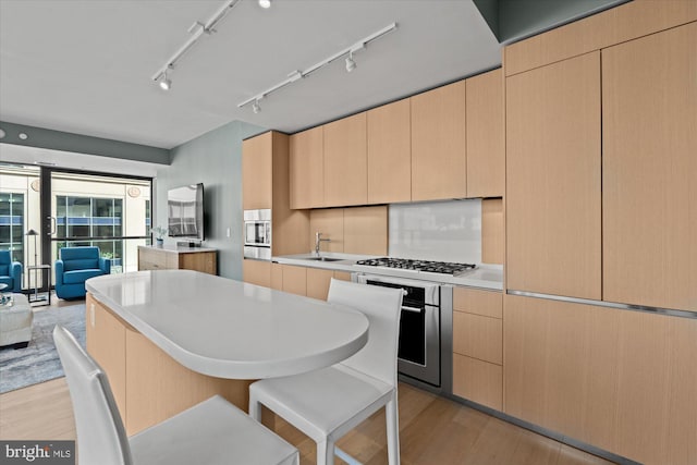 925 H St NW Unit 810, Washington, DC 20001 - kitchen with stainless steel appliances, light brown cabinetry, light wood-style flooring, a kitchen bar, and light countertops