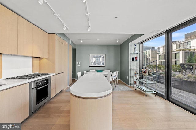 925 H St NW Unit 810, Washington, DC 20001 - kitchen featuring light brown cabinetry, stainless steel appliances, light wood-style floors, a kitchen island, and modern cabinets