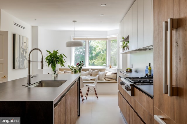 1914 35th St NW, Washington, DC 20007 - kitchen featuring modern cabinets, stainless steel gas stovetop, an island with sink, light tile patterned flooring, and decorative light fixtures