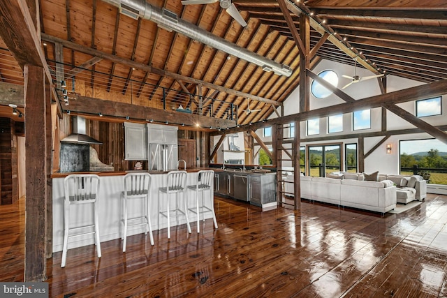 820 Spring Hill Rd, Riegelsville, PA 18077 - kitchen with high vaulted ceiling, wall chimney exhaust hood, appliances with stainless steel finishes, a peninsula, and dark wood-style floors