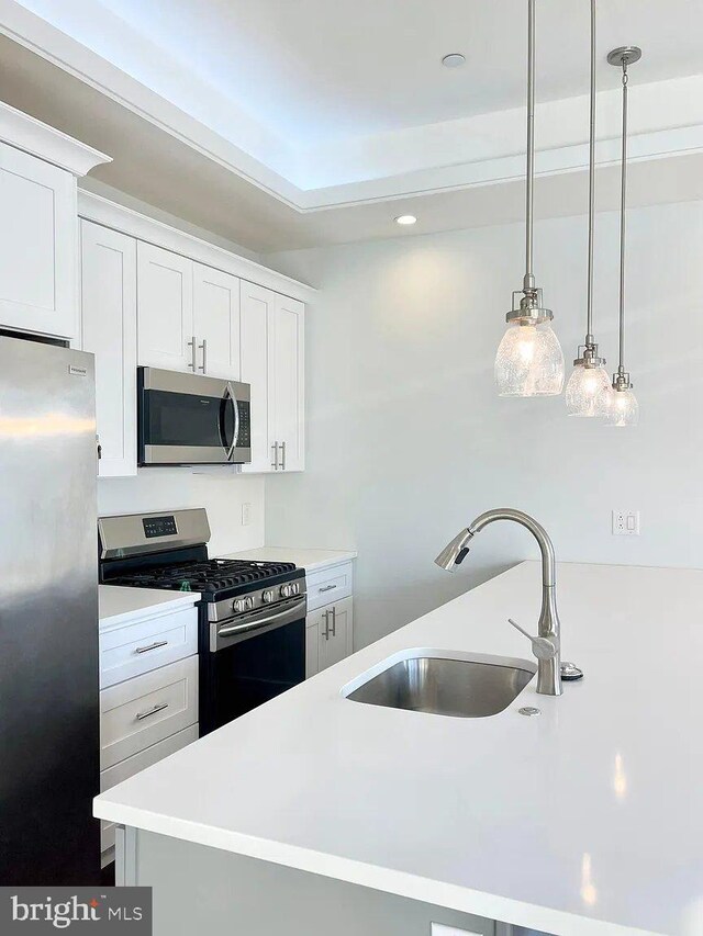 1337 N Franklin St, Philadelphia, PA 19122 - kitchen featuring appliances with stainless steel finishes, a sink, light countertops, white cabinetry, and hanging light fixtures