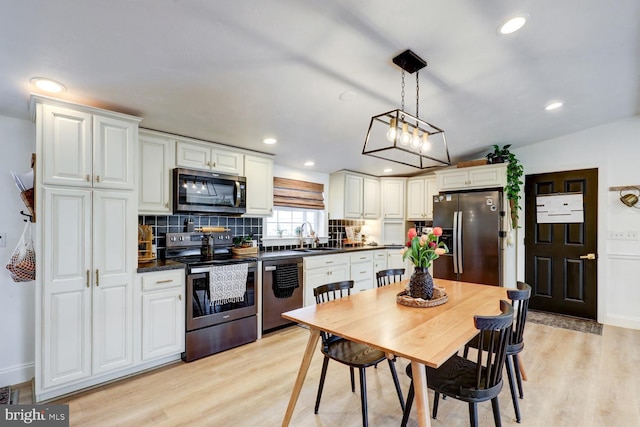 343 N Locust St, Myerstown, PA 17067 - kitchen with appliances with stainless steel finishes, dark countertops, a sink, decorative backsplash, and light wood-style floors