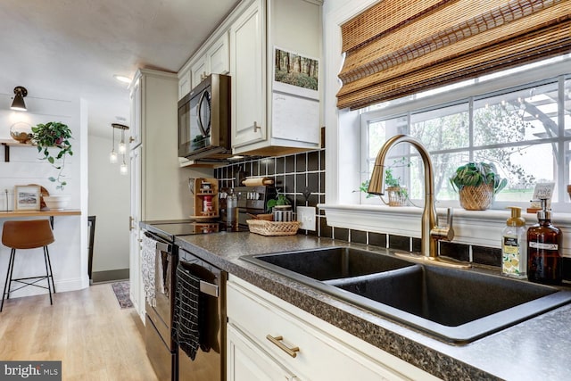 343 N Locust St, Myerstown, PA 17067 - kitchen with stainless steel appliances, a sink, dark countertops, backsplash, and white cabinets