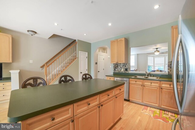 3627 Singleton Ter, Frederick, MD 21704 - kitchen featuring appliances with stainless steel finishes, dark countertops, a sink, light wood-style flooring, and arched walkways