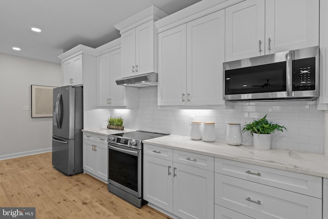 6978 Bray Rd, Hayes, VA 23072 - kitchen with appliances with stainless steel finishes, under cabinet range hood, white cabinetry, light wood finished floors, and decorative backsplash