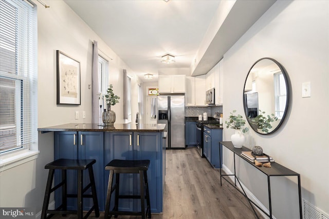 57 E Heath St, Baltimore, MD 21230 - kitchen with appliances with stainless steel finishes, a peninsula, blue cabinetry, dark countertops, and a kitchen breakfast bar