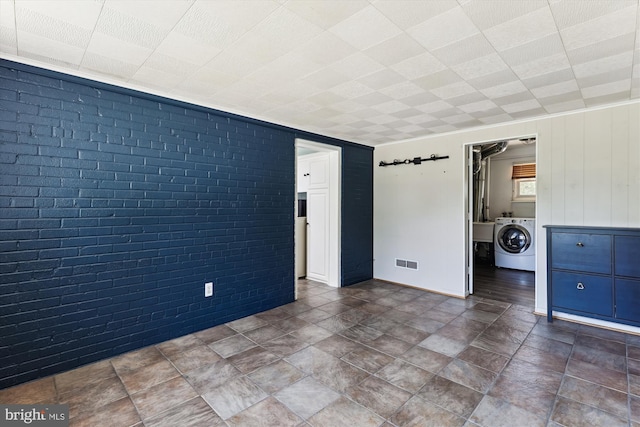 5214 Juliet St, Springfield, VA 22151 - empty room featuring washer / dryer, brick wall, and stone finish flooring
