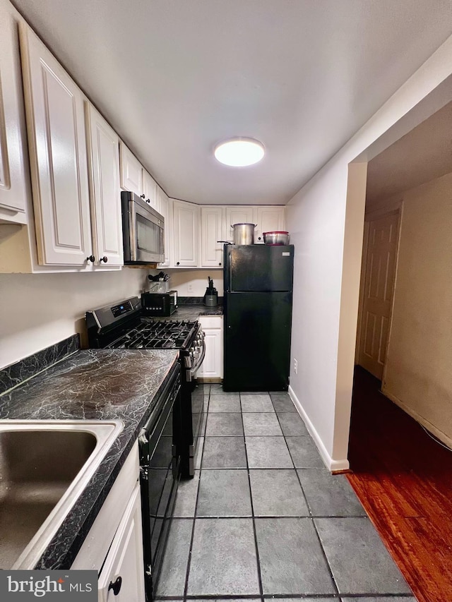 2634 Bowen Rd SE Unit 101, Washington, DC 20020 - kitchen with freestanding refrigerator, stainless steel microwave, gas stove, dark countertops, and white cabinets