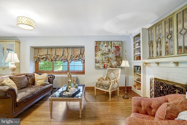 2305 S Inge St S, Arlington, VA 22202 - living room with radiator heating unit, wood finished floors, baseboards, built in shelves, and a brick fireplace