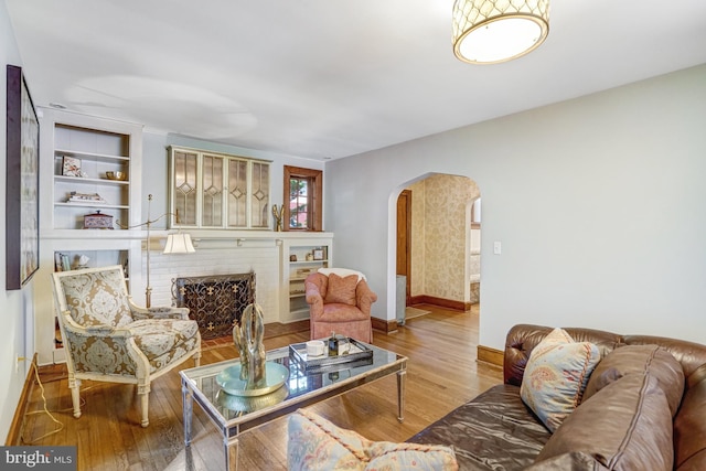 2305 S Inge St S, Arlington, VA 22202 - living room featuring arched walkways, wood finished floors, baseboards, and a brick fireplace