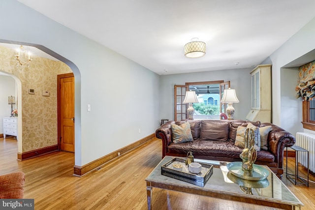 2305 S Inge St S, Arlington, VA 22202 - living room featuring arched walkways, radiator, light wood finished floors, and baseboards