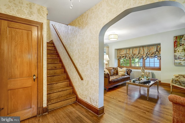2305 S Inge St S, Arlington, VA 22202 - stairway featuring wallpapered walls, arched walkways, radiator heating unit, hardwood / wood-style flooring, and baseboards