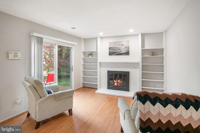 261 E Juniper Ave, Sterling, VA 20164 - living area with light wood-style flooring, a brick fireplace, a textured ceiling, recessed lighting, and baseboards