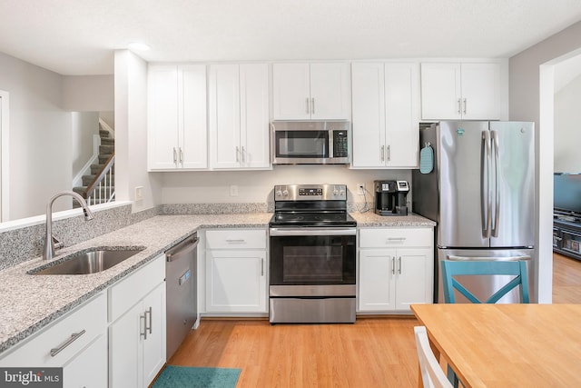 261 E Juniper Ave, Sterling, VA 20164 - kitchen with appliances with stainless steel finishes, a sink, white cabinetry, light wood-type flooring, and light stone counters