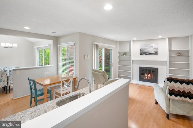 261 E Juniper Ave, Sterling, VA 20164 - living area with light wood-type flooring, a glass covered fireplace, recessed lighting, a textured ceiling, and a chandelier