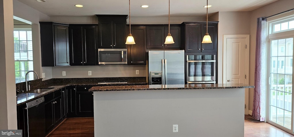 41056 Coltrane Sq, Leesburg, VA 20175 - kitchen with stainless steel appliances, a sink, dark stone countertops, a kitchen island, and wood finished floors