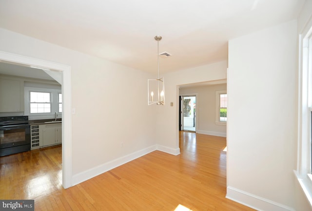 31 W Whitlock Ave, Winchester, VA 22601 - unfurnished dining area featuring a sink, a chandelier, light wood-style flooring, baseboards, and healthy amount of natural light