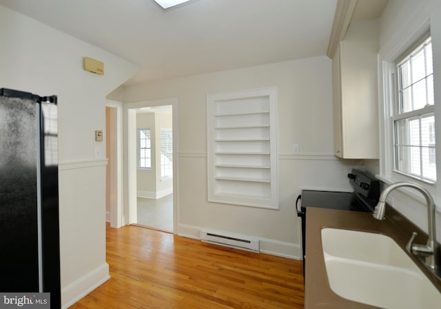 31 W Whitlock Ave, Winchester, VA 22601 - kitchen with a baseboard heating unit, freestanding refrigerator, a sink, light wood finished floors, and built in features