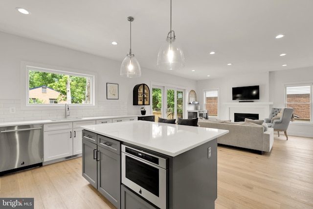 5421 4th St S, Arlington, VA 22204 - kitchen with stainless steel dishwasher, a sink, light wood-style floors, tasteful backsplash, and a kitchen island