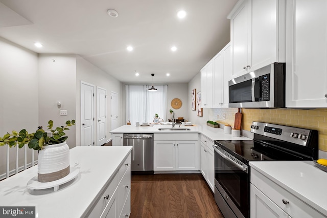 229 S Macon St, Baltimore, MD 21224 - kitchen with stainless steel appliances, a sink, a peninsula, dark wood-type flooring, and backsplash