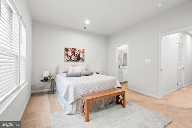 229 S Macon St, Baltimore, MD 21224 - bedroom featuring light colored carpet, multiple windows, baseboards, and connected bathroom