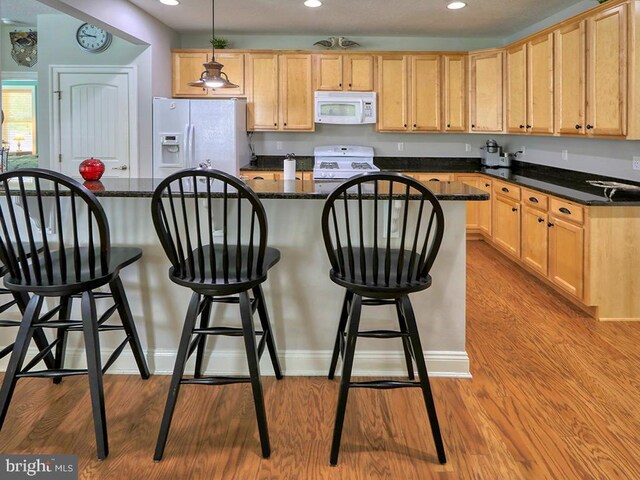 37529 Atlantic Ave Unit 11, Rehoboth Beach, DE 19971 - kitchen featuring white appliances, recessed lighting, light brown cabinets, wood finished floors, and a breakfast bar area