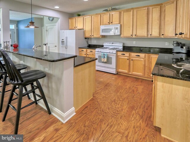 37529 Atlantic Ave Unit 11, Rehoboth Beach, DE 19971 - kitchen featuring white appliances, light wood-style floors, recessed lighting, a breakfast bar, and decorative light fixtures