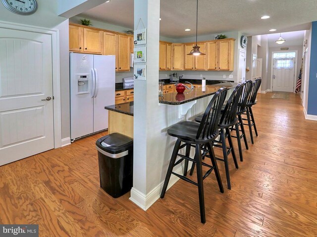 37529 Atlantic Ave Unit 11, Rehoboth Beach, DE 19971 - kitchen with white refrigerator with ice dispenser, light brown cabinetry, light wood-style flooring, a breakfast bar, and recessed lighting